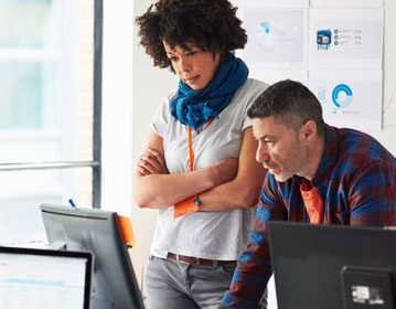 Coworkers conferring by a computer monitor